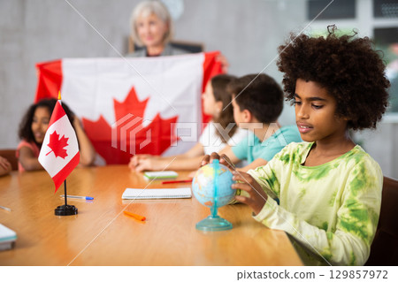 Female teacher showing canadian flag to kids in geography class Female teacher showing canadian flag to kids in geography class 129857972