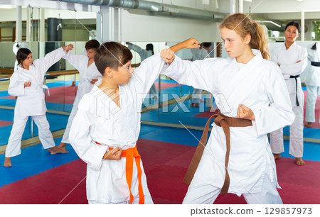 Boys and girls exercising karate moves on group training Boys and girls exercising karate moves on group training 129857973