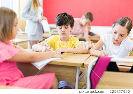 Preteen schoolchilds working in groups at lesson 129857990