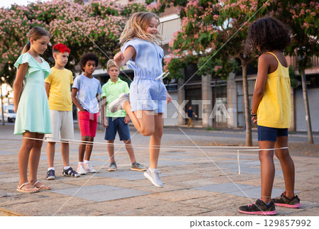 Kids playing with chinese jumping rope outdoors 129857992