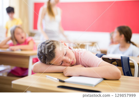 Schoolboy sleeping during lesson Schoolboy sleeping during lesson 129857999