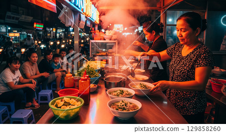 A Vendor Preparing Pho at a Vietnamese Street Food Stall at Night 129858260