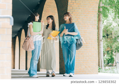 Three female university students walking on campus 129858302