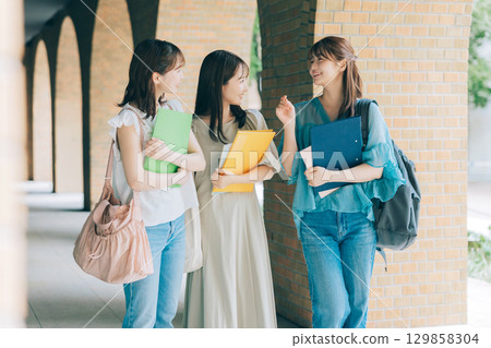 Three female university students walking on campus 129858304
