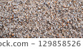 texture of sand on the beach is macro. Background with a sandy pattern with pebbles on beach by the sea closeup 129858526