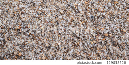 texture of sand on the beach is macro. Background with a sandy pattern with pebbles on beach by the sea closeup 129858526