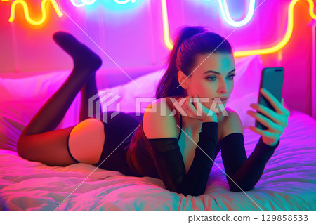 beautiful sexy young girl webcam model in sexual lingerie chats and sexting on a mobile smartphone lying on bed in the bedroom beautiful sexy young girl webcam model in sexual lingerie chats and sexting on a mobile smartphone lying on bed in the bedroom 129858533