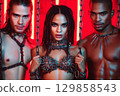 Sexy mistress woman with two submissive men in chains. BDSM sex with submission and domination 129858543