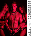 sexual man with two submissions sexy women in chains. The concept of BDSM sex with domination and submission 129858546