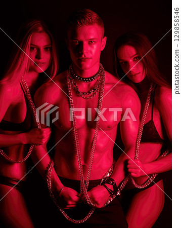 sexual man with two submissions sexy women in chains. The concept of BDSM sex with domination and submission 129858546