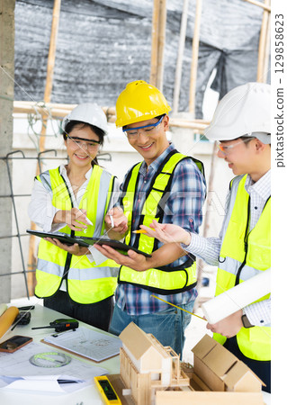 Engineer teams meeting working together wear worker helmets hardhat on construction site in city. Engineer teams meeting working together wear worker helmets hardhat on construction site in city. 129858623