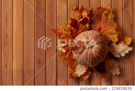 Autumn Pumpkin with Colorful Leaves on Wooden Background. File with Clipping Path. 129858630