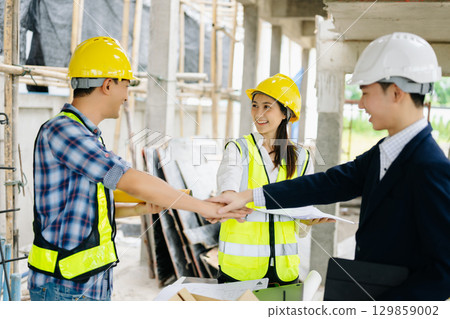 Contractor and architect looking at plan, tablet, laptop and talking about working on big project. Contractor and architect looking at plan, tablet, laptop and talking about working on big project. 129859002