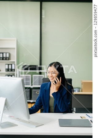 Asian woman sitting at a desk using a laptop computer Navigating Finance and Marketing 129859477