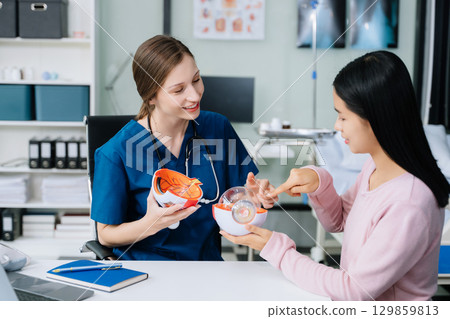 Portrait of female doctor explaining diagnosis to her patient. Doctor Meeting With Patient In Exam Room. Portrait of female doctor explaining diagnosis to her patient. Doctor Meeting With Patient In Exam Room. 129859813