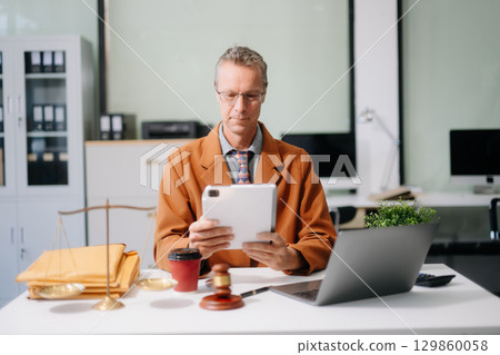 justice and law concept. Male judge in a courtroom the gavel, working with smart phone and laptop 129860058