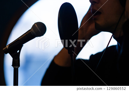 一名年輕男子正在接受聲音訓練和錄音。沒有臉。 一名年輕男子正在接受聲音訓練和錄音。沒有臉。 129860552