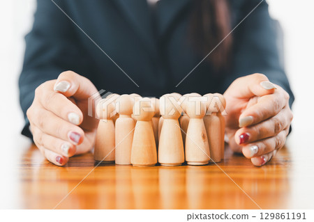 Hands protecting family wooden model for insurance and assurance life concept. Businessman hand gesture protecting wooden domino falling to family dolls for insurance and assurance. Hands protecting family wooden model for insurance and assurance life concept. Businessman hand gesture protecting wooden domino falling to family dolls for insurance and assurance. 129861191