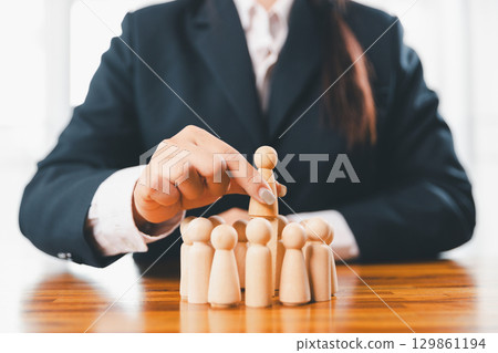 Hands protecting family wooden model for insurance and assurance life concept. Businessman hand gesture protecting wooden domino falling to family dolls for insurance and assurance. 129861194