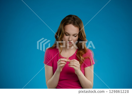 Woman expresses deep emotion while posing in a studio setting against a vibrant blue background 129861228