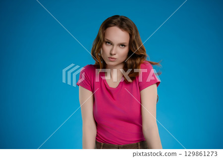 Woman posing in a studio with blue background conveying a range of emotions through her expression and body language Woman posing in a studio with blue background conveying a range of emotions through her expression and body language 129861273