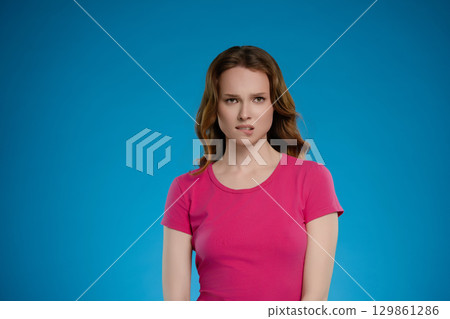 Woman posing in a studio setting showing a range of emotions against a bright blue backdrop 129861286