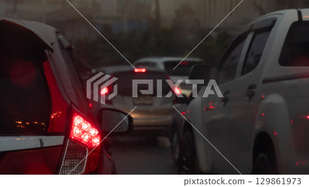 Abstract traffic conditions during the foggy rain. Rear side of cars with turn on brake light. Environment of traffic jam on rainy time with other cars. Heavy rainy time and dark sky. Abstract traffic conditions during the foggy rain. Rear side of cars with turn on brake light. Environment of traffic jam on rainy time with other cars. Heavy rainy time and dark sky. 129861973