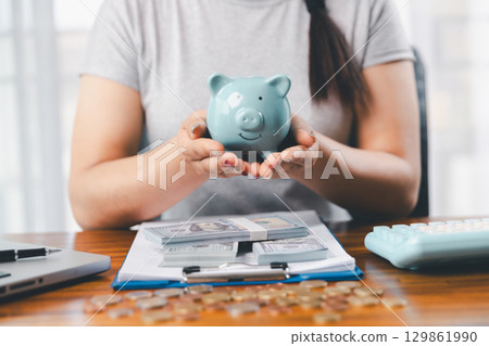 Businesswoman saving money with piggy bank and coins on desk, financial planning and investment concept. Young Asian woman making stack of coin. invest save finance concept, saving money, investment Businesswoman saving money with piggy bank and coins on desk, financial planning and investment concept. Young Asian woman making stack of coin. invest save finance concept, saving money, investment 129861990