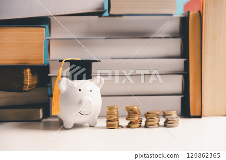 Concept of saving money for education, student loan, scholarship in future. Piggy bank with graduation hat, stack of coins. Earth globe with graduation hat, dollar banknotes on table. Tuition fees 129862365