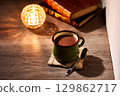 Warm hot chocolate and tealight candles on a table with an autumnal feel 129862717