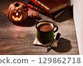 Warm hot chocolate and jack-o'-lanterns on a table in an autumnal setting 129862718