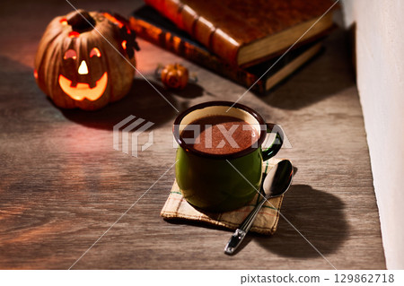 Warm hot chocolate and jack-o'-lanterns on a table in an autumnal setting 129862718