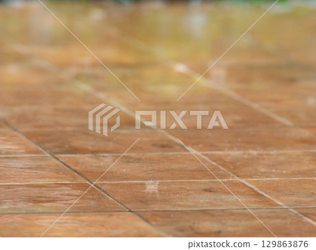 Gentle Rain falls on the brown tile floor. 129863876