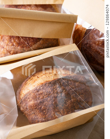 Sourdough Bread Loaf in Transparent Plastic Bag on White Background Ready for Sale or Delivery 129864074