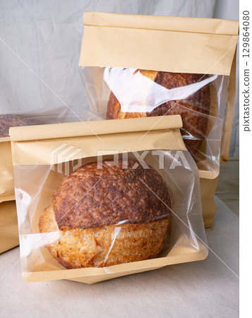 Sourdough Bread Loaf in Transparent Plastic Bag on White Background Ready for Sale or Delivery 129864080