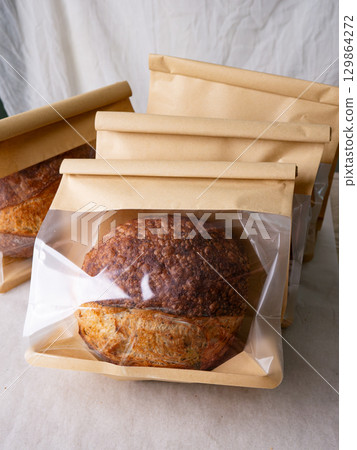 Sourdough Bread Loaf in Transparent Plastic Bag on White Background Ready for Sale or Delivery Sourdough Bread Loaf in Transparent Plastic Bag on White Background Ready for Sale or Delivery 129864272