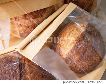Sourdough Bread Loaf in Transparent Plastic Bag on White Background Ready for Sale or Delivery 129864273