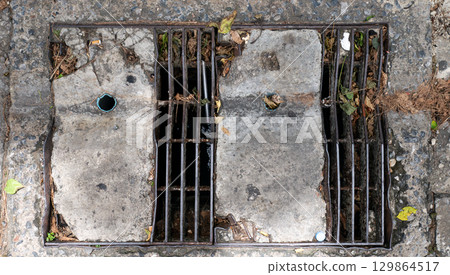 Old Rectangular Urban Drain Cover Made of Metal Grate and Concrete. Old Rectangular Urban Drain Cover Made of Metal Grate and Concrete. 129864517