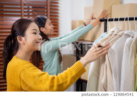 Two young asian woman checking stock clothes for delivery in office. 129864541