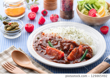 A fragrant tomato curry and rice served with salad - a home-cooked meal 129865492