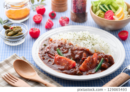A fragrant tomato curry and rice served with salad - a home-cooked meal 129865493