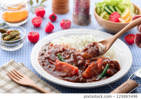 A fragrant tomato curry and rice served with salad - a home-cooked meal 129865496