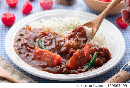 A fragrant tomato curry and rice served with salad - a home-cooked meal 129865499