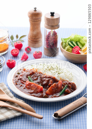 A fragrant tomato curry and rice served with salad - a home-cooked meal 129865503