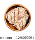 Grilled mackerel fillet, in its own juice, in a wooden bowl. Salted piece of mackerel, fried on a grill, preserved in the liquid that naturally extracts from the fish during the canning process. Photo 129865561