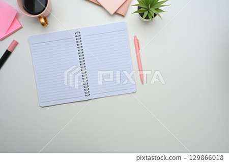 Feminine office desk scene with notebook, pen, coffee, and pink flowers Feminine office desk scene with notebook, pen, coffee, and pink flowers 129866018