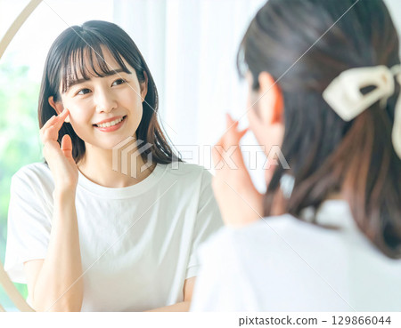 Young woman looking at a mirror 129866044