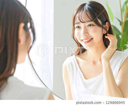 Young woman looking at a mirror 129866045