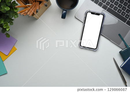 Blank screen smartphone, laptop, coffee cup, and office supplies on white desk Blank screen smartphone, laptop, coffee cup, and office supplies on white desk 129866087