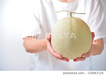 A woman offering a muskmelon (produced in Kumamoto Prefecture) 129867126